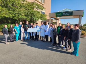 Coach Huggins presents $380K check to Mon Health Cancer Center